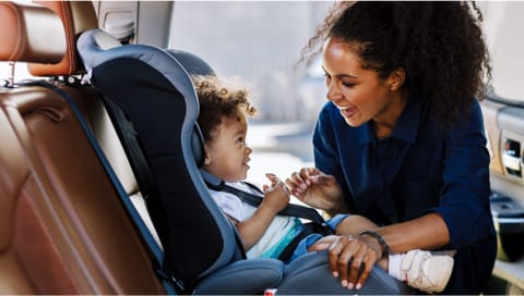 Mom buckling child in car seat