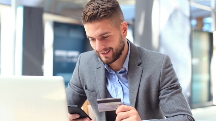 Person using a mobile phone and holding a corporate credit card