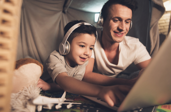 Father and son wearing headphones and looking at laptop